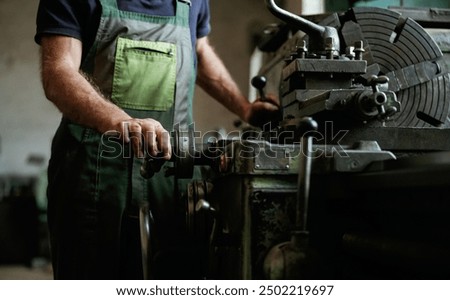 Side view. Close-up of worker's hands operating industrial machinery in workshop.