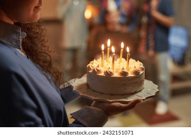 Side view closeup of young woman holding Birthday cake with lit candles at home celebration copy space - Powered by Shutterstock