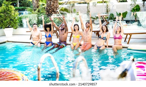 Side view composition of friends sitting at hotel swimming pool wearing swim clothes - Summer life style concept with trendy people having fun on sunny day at luxury poolside - Bright vivid filter
