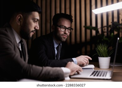 Side view of computer systems analysts using charts on computer monitors while working in office