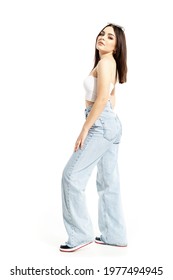 Side View Of Confident Attitude Young Woman In Jeans And White Top Posing At Camera. Full Body Length Isolated On White Background