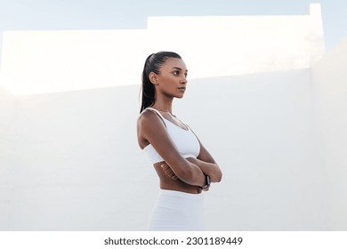 Side view of a confident female athlete standing outdoors. Fitness woman with crossed hands standing confidently during exercises. - Powered by Shutterstock