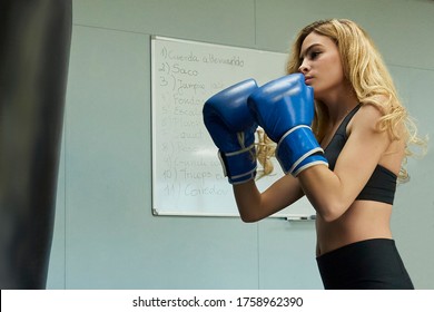 Side View Of Confident Female Boxer Exercising In Gym