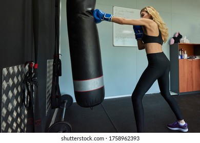 Side View Of Confident Female Boxer Exercising In Gym