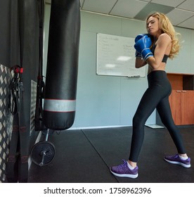 Side View Of Confident Female Boxer Exercising In Gym