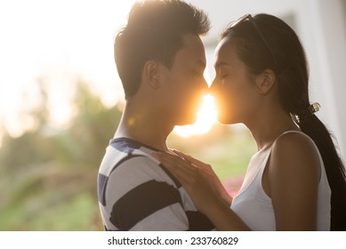 Side view of couple kissing while on the background of declining sun
