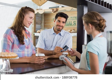 Side View Of A Couple Paying Bill At Coffee Shop Using Card Bill