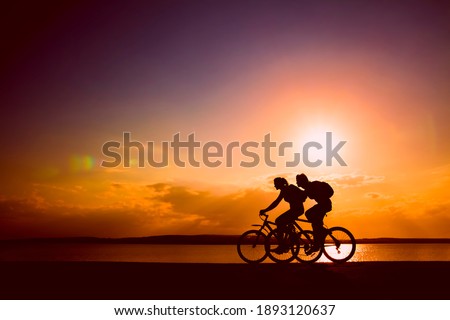 Side view of couple riding  on seashore with their bicycles. sunset sky on background. couple in love. silhouette of man and woman.