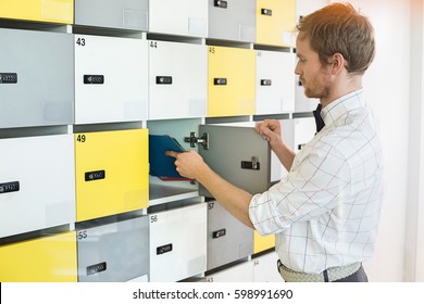 Side View Of Creative Businessman Putting Files In Locker At Office