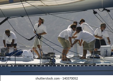 Side view of crew members working on sailboat