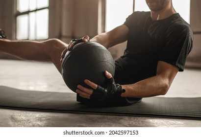 Side view of crop unrecognizable athletic male doing side twist exercise with medicine ball during intense functional training in gym - Shutterstock ID 2042597153