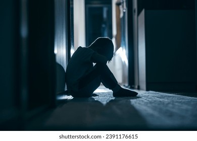 Side view of a crying little boy sitting in a dark room at home. Back lit. - Powered by Shutterstock