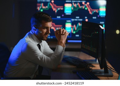 Side view of crypto broker sitting at office table, analyzing market, looking at screen. - Powered by Shutterstock