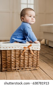 Side View Of Cute Little Baby Boy Sitting Inside Of Braided Box At Home