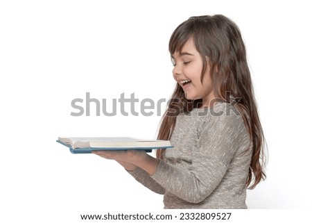 Side view of cute long haired tanned girl laughing over open book in her hands. Free space for your text.