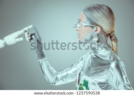 side view of cyborg touching robotic arm isolated on grey, future technology concept