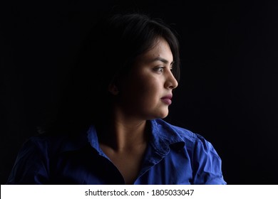 Side View Of Dark Portrait Of A Latin Woman On Black Background, Serious