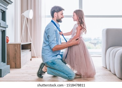 Side View Of Daughter Tying Tie On Her Father Standing Face To Face In Living Room