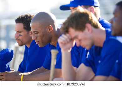 Side View Of A Dejected Baseball Team In Blue Uniform Sitting On The Bench In The Stand During A Competitive Baseball Game.