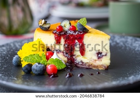 Side view of delicious blueberries cheese cake well decorated with berries, mint and jam in high cuisine restaurant.
