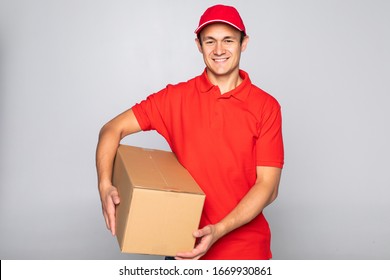 Side View Of Delivery Man With Box In Studio. Isolated Gray Background