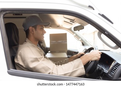Side view of delivery man with cardboard boxes sitting in front seat of car outside the warehouse. This is a freight transportation and distribution warehouse. Industrial and industrial workers