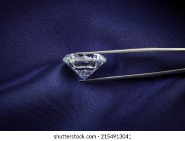 Side View of Diamond Held in Tweezers on Dark Blue Silk Background - Shutterstock ID 2154913041
