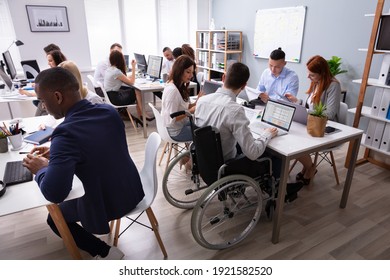 Side View Of A Disabled Businessman Sitting On Wheelchair Using Laptop Working In Office