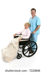 Side View Of A Disabled Senior Woman Being Pushed In Her Wheelchair By A Doctor Or Male Nurse.  Full Body Isolated On White.