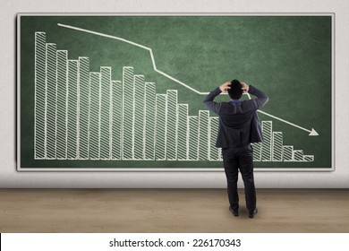 Side view of disappointed businessman looking at chart showing economic recession - Powered by Shutterstock