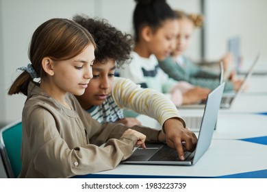 Seitenansicht bei verschiedenen Gruppen von Kindern, die im Schulunterricht in Reihe sitzen und Laptops verwenden