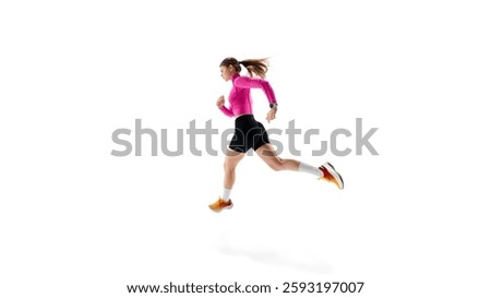 Side view dynamic image of young competitive woman, runner in motion, demonstrating agility, and focus against white studio background. Concept of athletics, sport, endurance, healthy lifestyle. Ad