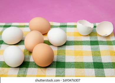 side view of eggs with eggshell on cloth surface and purple background