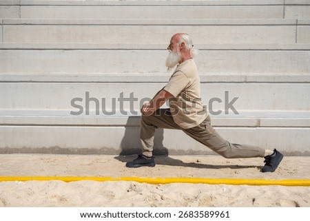 Side view of elderly man with long white beard doing lunge exerc