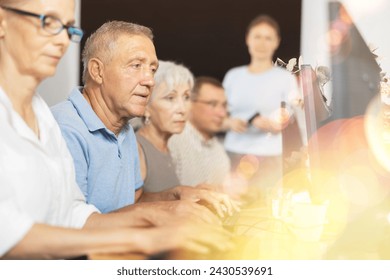 Side view of elderly people while studying in computer class in nursing home