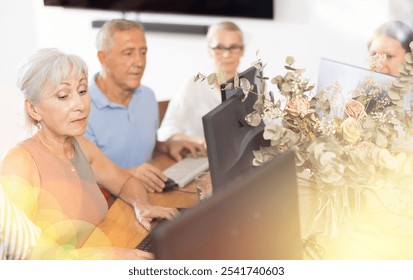 Side view of elderly people while studying in computer class in nursing home