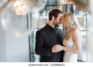 Side View Of Elegant Couple Holding Hands And Smiling In Restaurant