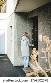 Side View Of Elegant French Woman Wearing Wool Coat Entering Apartment Building Open Door With Key Closing - Vertical Image