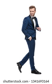 Side View Of Elegant Man In Blue Suit Walking While Looking Back With Hand In Pocket On White Background