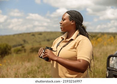 Side view of emale tour guide using binoculars and searching the landscape for wildlife in Africa - Shutterstock ID 2193216997