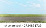 Side view of empty asphalt road and green field
