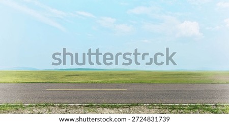 Side view of empty asphalt road and green field