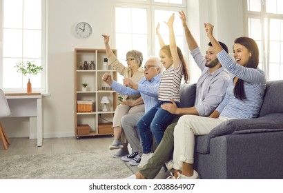 Side View Of An Excited Active Large Family Of Different Generations Watching A Football Match Or Other Sporting Event Together While Sitting On The Couch At Home. Concept Of Human Emotions.