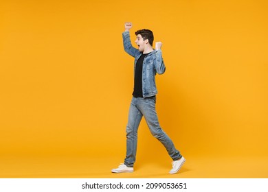 Side View Of Excited Young Man Guy Wearing Casual Denim Clothes Posing Isolated On Yellow Background Studio Portrait. People Lifestyle Concept. Mock Up Copy Space. Expressive Gesticulating With Hands