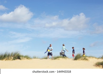 Side View Of Family Walking Sand Dune On Beach Against The Sky