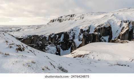 Side view of the famous Icelandic Fjadrargljufur, Fjaðrárgljúfur canyon during winter. Snowy canyon, rocky volcanic cliffs. Famous must-see touristic spot. Wonderful Icelandic landscape. Soft light. - Powered by Shutterstock