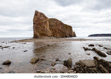 Side View Of The Famous Limestone Percé Rock In The Gaspé Peninsula Seen At Low Tide During A  Cloudy Afternoon, Quebec, Canada