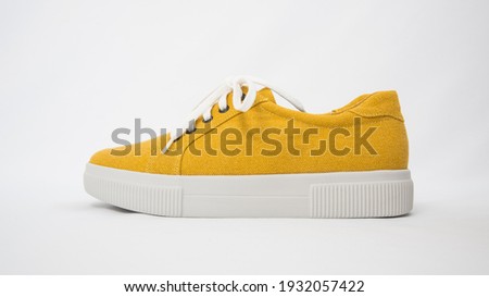 Side view of fashionable mustard-colored shoes. Sneakers on a white background. The shoe fabric is made from recycled textiles. Eco-friendly comfort. The concept of caring for the environment