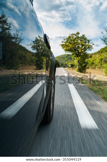 Side\
view of the fast driving car on the country\
road