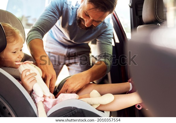 Side view of father securing child to a baby\
car seat                              \
